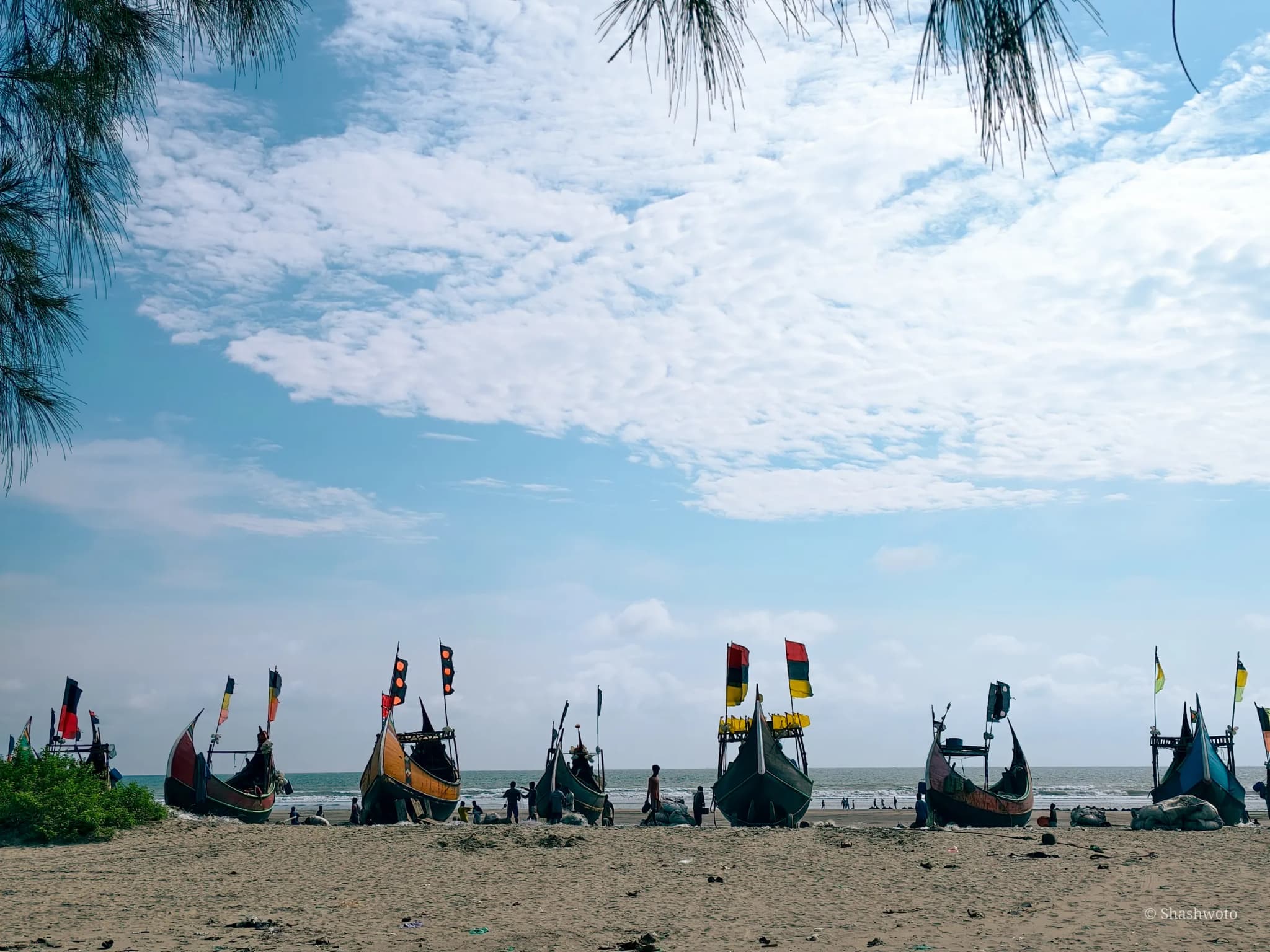 Wide perspective of fishing boats with colorful flags along the open beach
