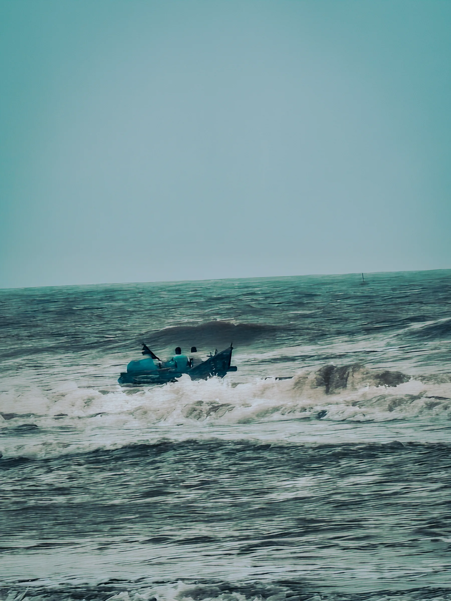 Small wooden boat carrying crew navigating whitecaps and turbulent sea waves